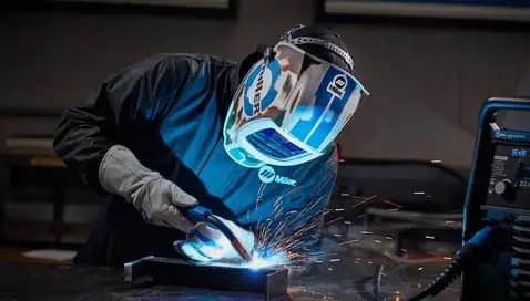 A man in a welding helmet creating internal threads without breaking the taps