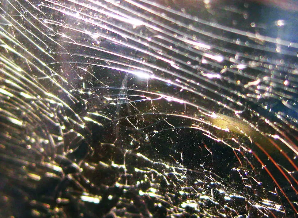 Highly magnified image of scratched and fractured plastic showing intricate light reflections and patterns Highly magnified image of scratched and fractured plastic showing intricate light reflections and patterns