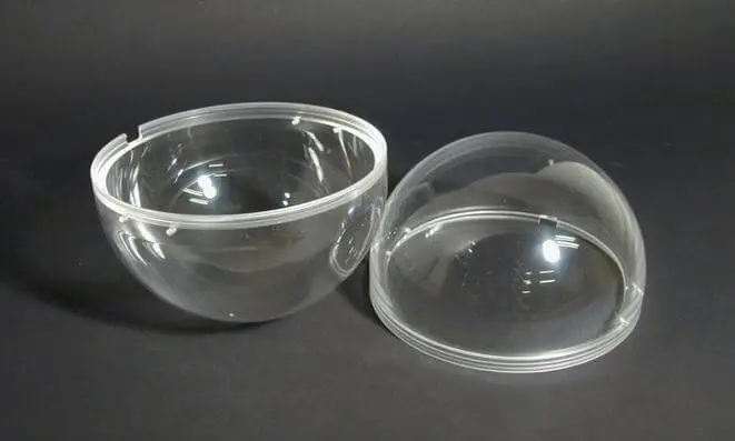 Two clear acrylic domes one placed open and the other positioned upside down displayed on a dark surface Two clear acrylic domes one placed open and the other positioned upside down displayed on a dark surface