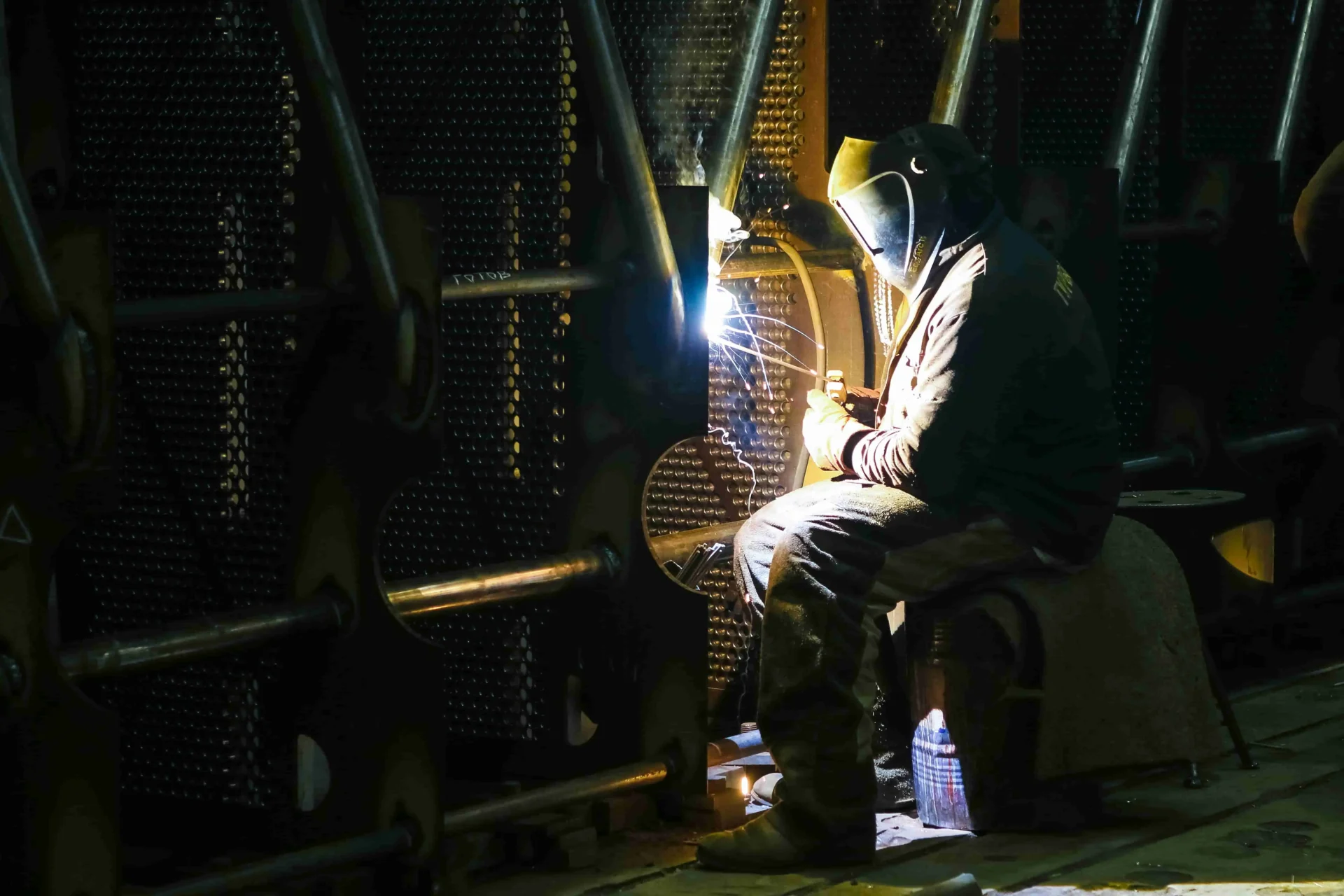 Worker welding in a dark industrial setting focusing on precision Worker welding in a dark industrial setting focusing on precision
